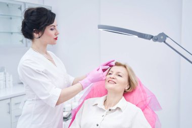 Güzellik iğnesi yapan konsantre kadın.