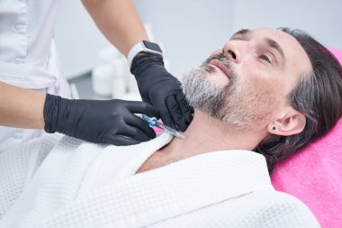 Cilt düzeltmesi yapan sakallı adama odaklanmış bir fotoğraf.