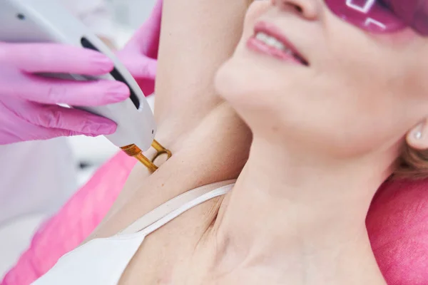 Cosmetologist removing hair from woman armpit with laser device — Stock Photo, Image
