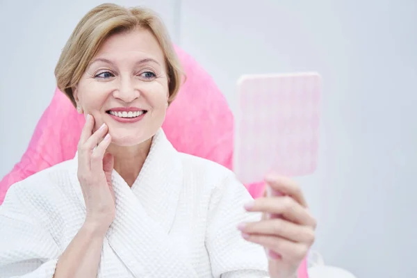 Femme gaie regardant dans le miroir dans le salon de beauté — Photo