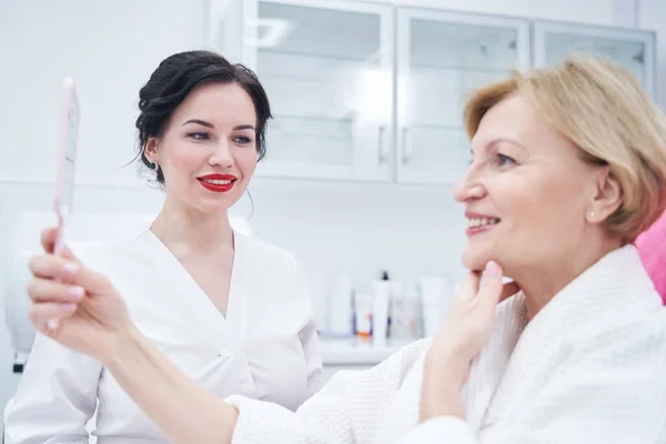 Cheerful beautician looking at woman in beauty salon — Stock Photo, Image