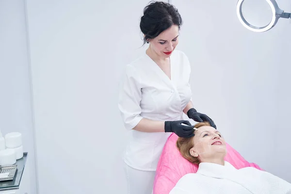 Cosmetologist drawing line on woman face in beauty salon — 스톡 사진