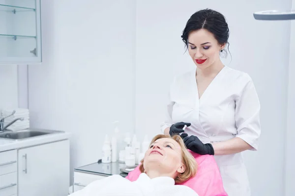 Tricólogo femenino inyectándose en el cuero cabelludo de la mujer en el centro de belleza — Foto de Stock