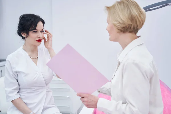Cosmetologist bonito examinando seu paciente no armário — Fotografia de Stock