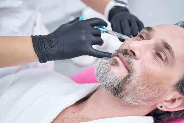 İşlem için steril şırınga kullanan profesyonel bir kozmetikçi