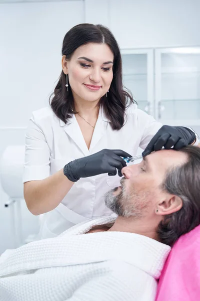 Pleased beauty master working with patient in clinic — Stock Photo, Image