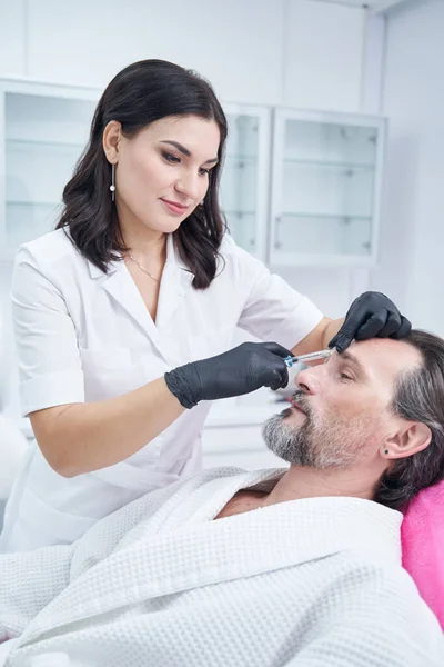 Positive delighted cosmetologist working in aesthetic medicine — Stockfoto