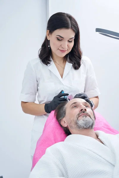 Delighted cosmetologist doing mesotherapy for her patient — Stock Photo, Image