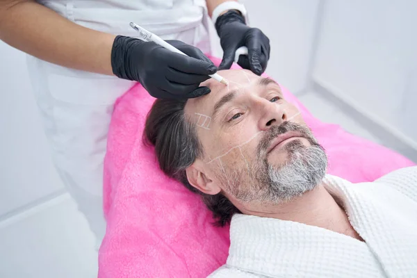 Adult man visiting beauty clinic for doing facelifting — Stock Photo, Image