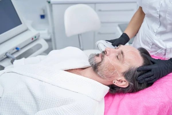 Relaxed male person doing face lifting procedure — Stock Photo, Image