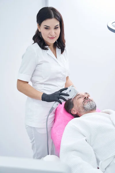 Verheugd kosmetoloog werkt met moderne laserapparatuur — Stockfoto