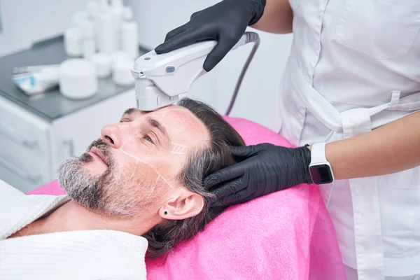 Hasta için cilt bakımı yapan profesyonel bir kozmetolog.