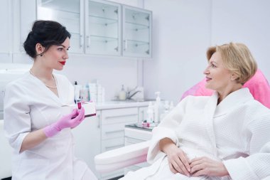 Kadın güzellik kliniğinde kozmetikçiyle görüşüyor.