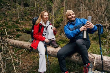 Termoslu bir adam akıllı telefondan dışarıdaki kadınlara fotoğraf gösteriyor.