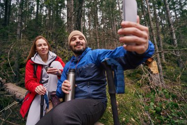 Two hikers on tree making selfie in the woods