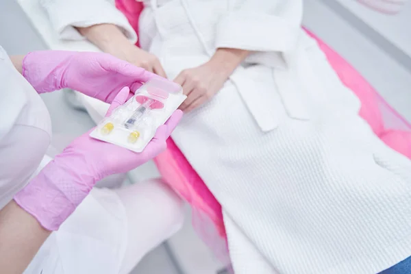 Beautician showing cosmetic syringe to woman in beauty clinic — Fotografia de Stock