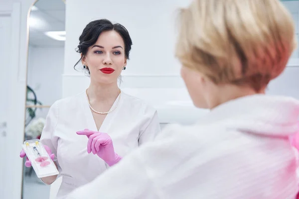 Kosmetikerin zeigt Frau im Schönheitssalon Spritze — Stockfoto