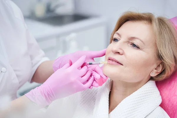 Cosmetoloog het maken van schoonheid injectie in vrouwelijke lippen — Stockfoto