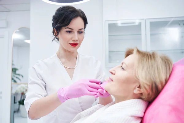 Mujer adulta que recibe inyección labial en clínica de cosmetología — Foto de Stock