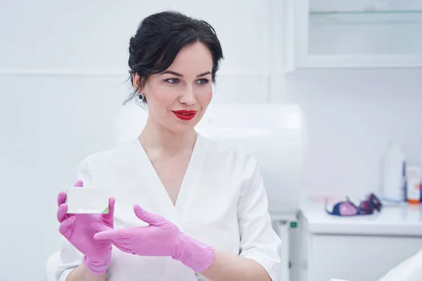Female beautician holding cosmetic cream in beauty salon — Zdjęcie stockowe