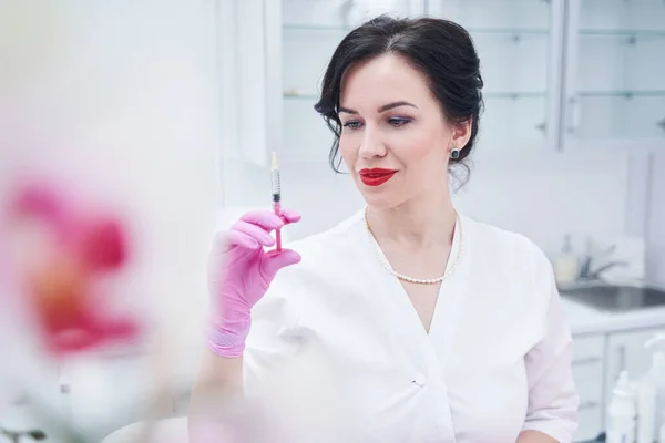 Mujer cosmetóloga sosteniendo jeringa en salón de belleza —  Fotos de Stock