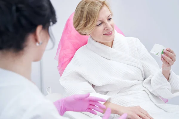Joyful woman holding cosmetic cream in beauty salon — ストック写真