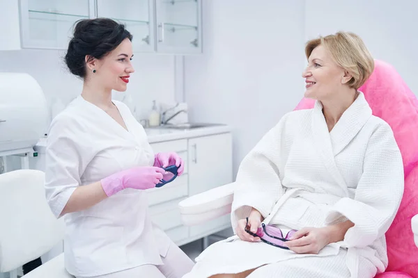 Vreugdevolle vrouw in overleg met arts in kosmetologische kliniek — Stockfoto