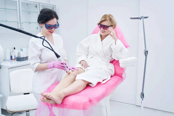 Mujer alegre recibiendo tratamiento de depilación láser en salón de belleza — Foto de Stock