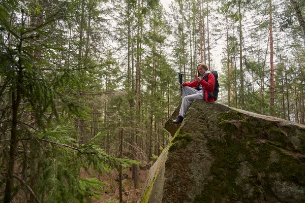 암컷 트레커 가 숲 속 바위 꼭대기에 있는 스마트폰을 확인하는 모습 — 스톡 사진