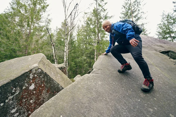미끄러지면서 바위 가장자리를 잡고 있는 남자 관광객 — 스톡 사진