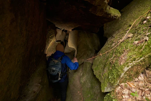 Άνθρωπος που πηγαίνει μέσα σε σπηλιά μέσα σε βράχους στο δάσος — Φωτογραφία Αρχείου