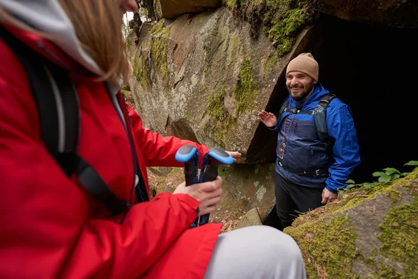 Neşeli erkek gezgin mağaradan çıktıktan sonra kadına el sallıyor.