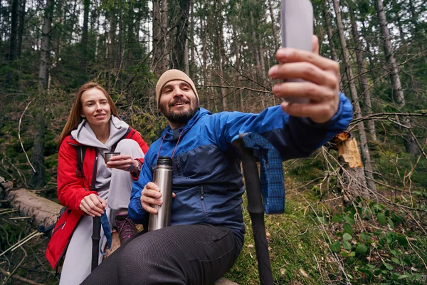 Deux randonneurs sur l'arbre faisant du selfie dans les bois — Photo