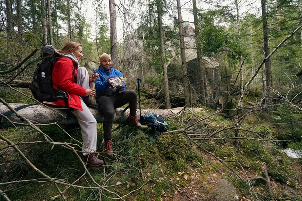 Paire de randonneurs qui mordent sur un arbre tombé — Photo