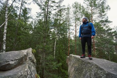 Tourist standing on rock edge inside forest