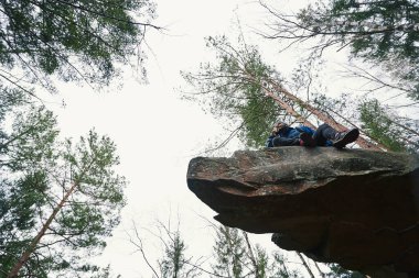 Uçurumdaki orman yürüyüşçüsünün akıllı telefonlu alt görüntüsü