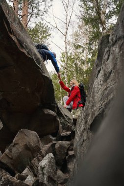 Kayadan inerken erkek yürüyüşçüyü destekleyen kadın