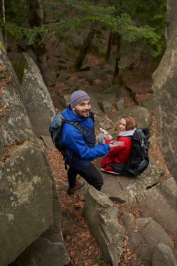 Dinlenme yerinde pusula kullanan neşeli bir adam.