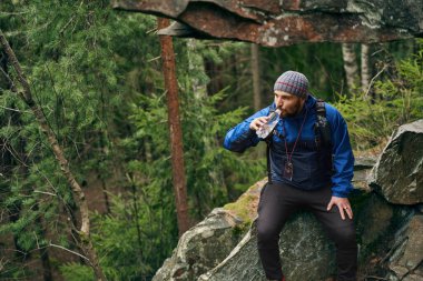 Gezgin, doğada otururken bir yudum su içiyor.