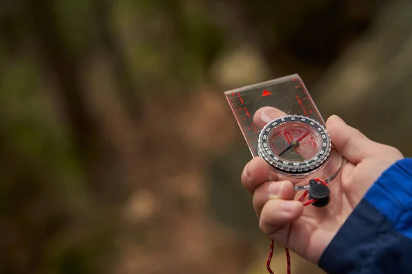 Liquid-filled compass in hand of tourist inside forest — Stok fotoğraf