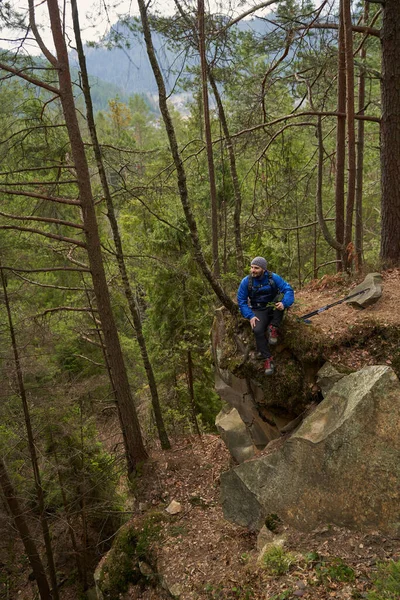 Erkek, yürüyüş sırasında kayalık kayalıklarda dinleniyor.
