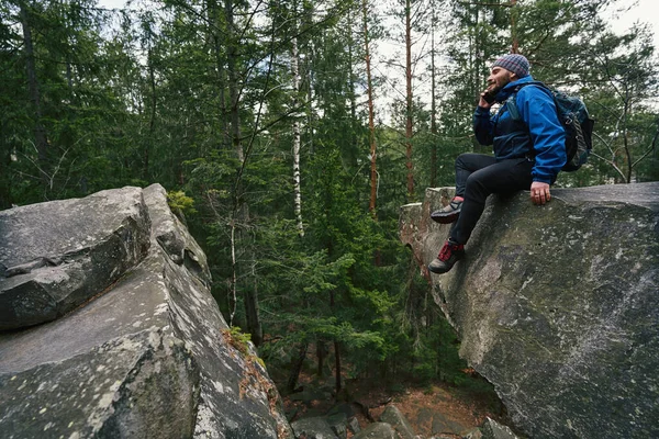 숲 속 바위 위에서 전화를 받고 있는 도보 여행자 — 스톡 사진