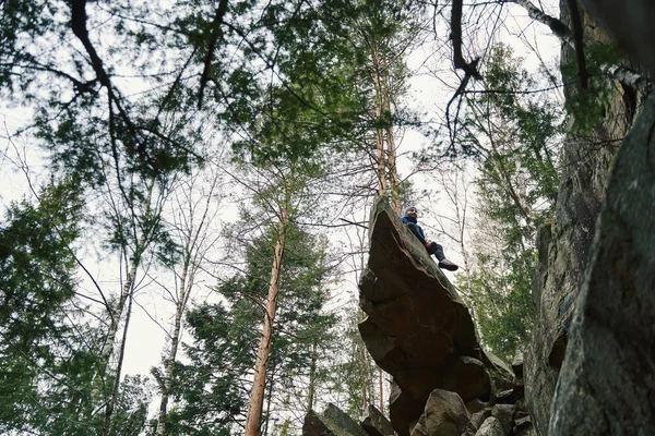 Плідна людина на вершині величезної скелі в лісі — стокове фото