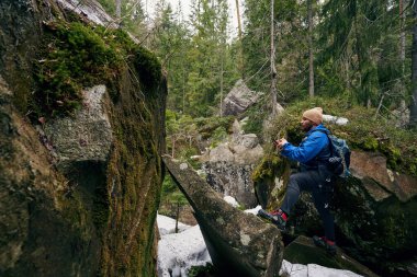 Kayanın üzerinde duran sırt çantalı aktif gezgin.