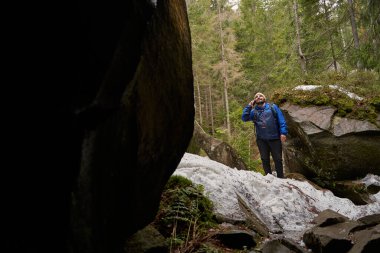 Kayanın yakınındaki karlı yüzeyde duran aktif turist