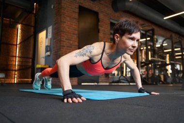 Kaslı kadın spor salonunda şınav çekiyor.