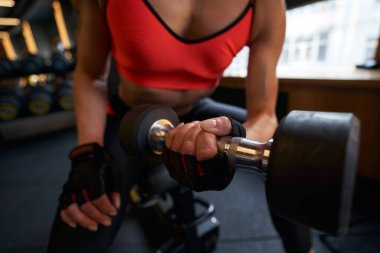 Sporcu kadın spor salonunda el ağırlığıyla çalışıyor.