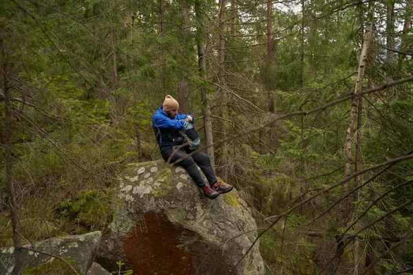젊은 남자 모험가가 바위 위에 앉아 — 스톡 사진