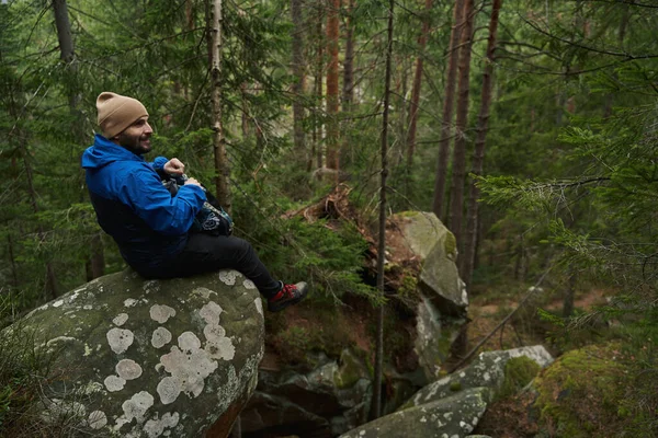 Viajante feliz sentado na rocha na floresta — Fotografia de Stock