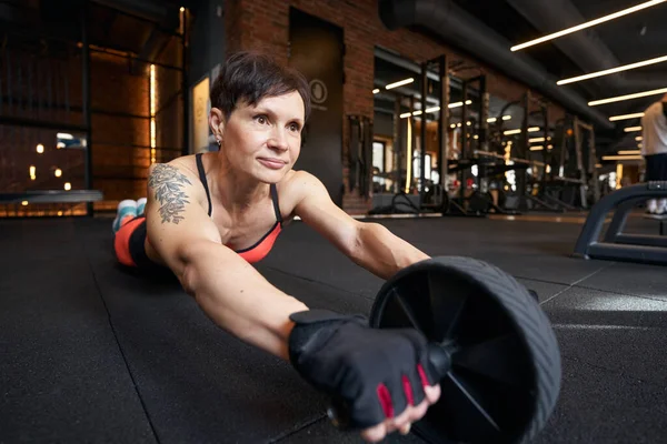 Deportiva haciendo ab rueda de despliegue en el piso del gimnasio — Foto de Stock